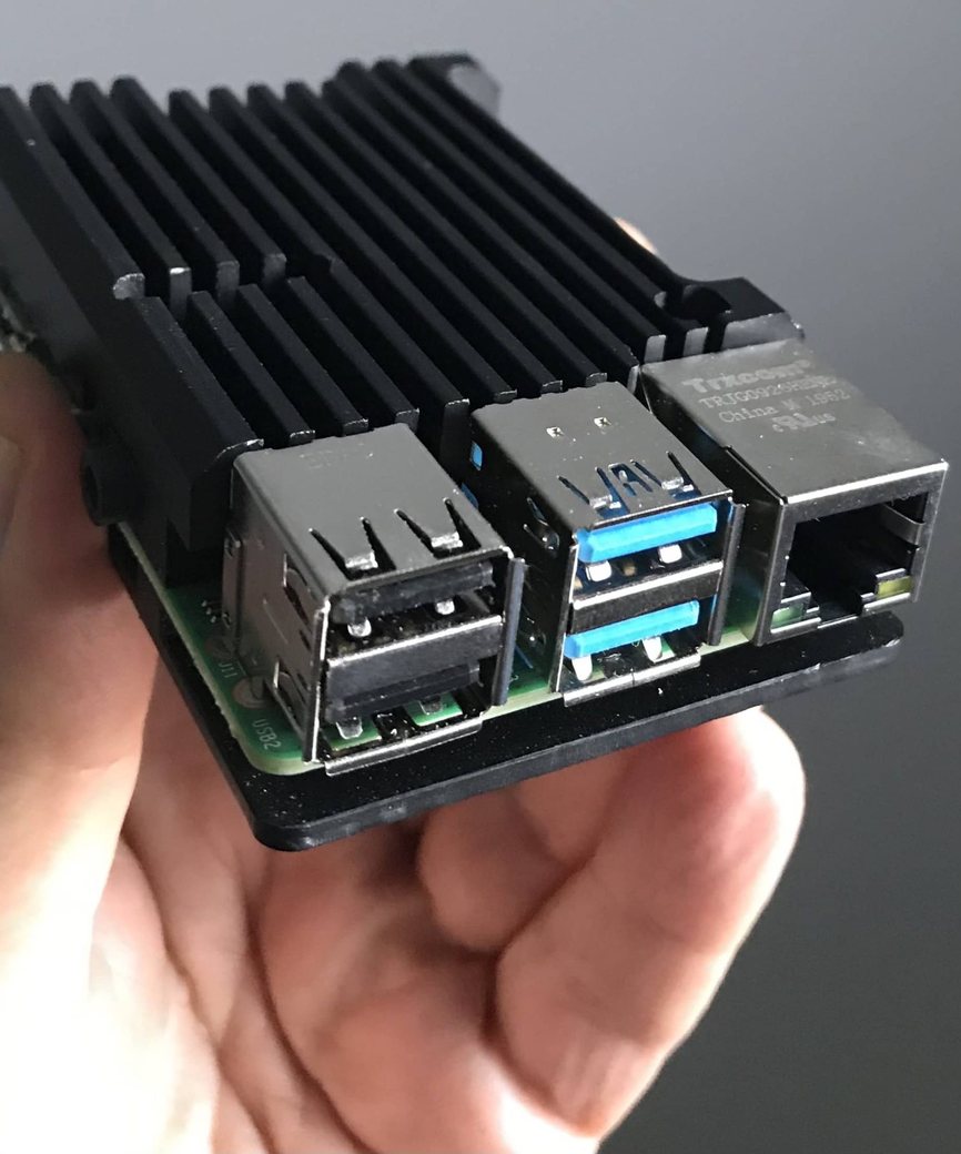 Hand holding a compact single-board computer in an aluminium heatsink case